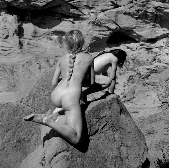 Rear view of shirtless woman lying on rock
