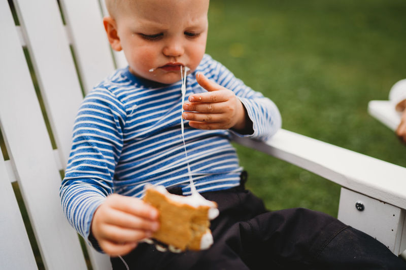 Male toddler eating smores with melted marshmallows