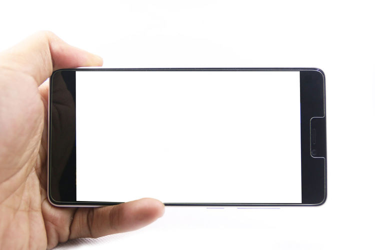 Midsection of person holding mobile phone against white background