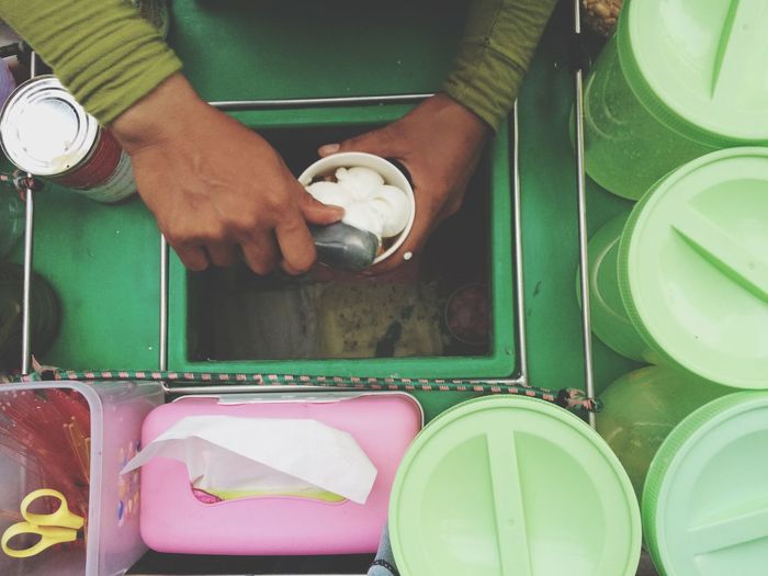 Cropped image of vendor filling coconut ice cream scoops in cup at concession stand