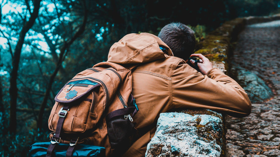 Rear view of man carrying backpack at forest