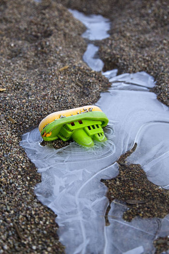 High angle view of toy boat on frozen water and sand at beach