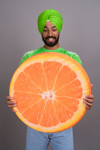 Man holding orange slice against gray background