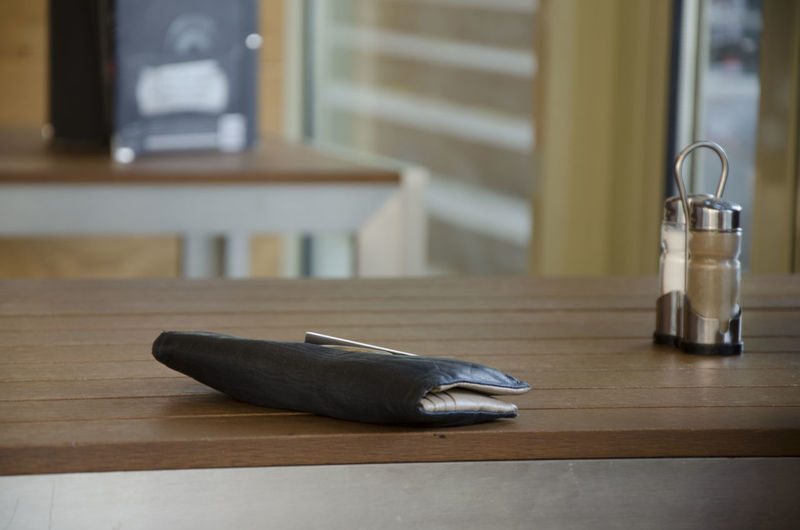 Close-up of wallet next to pepper shaker on table