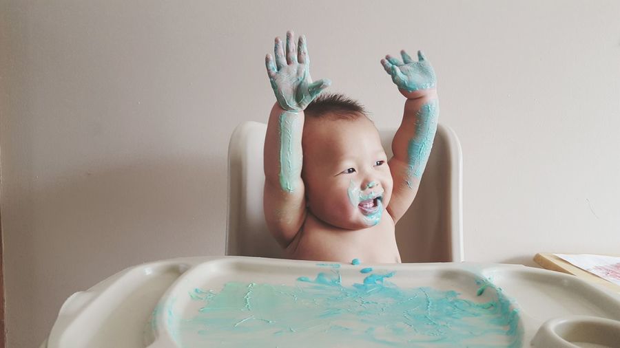 Baby boy playing with watercolor paints on table