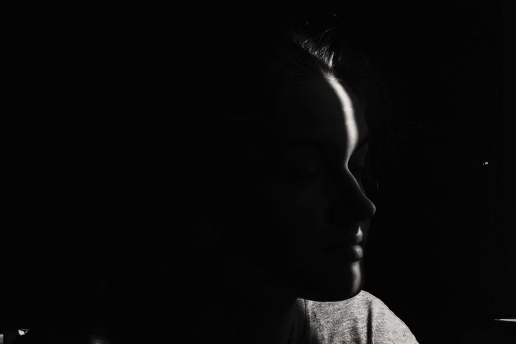Close-up of man looking away against black background
