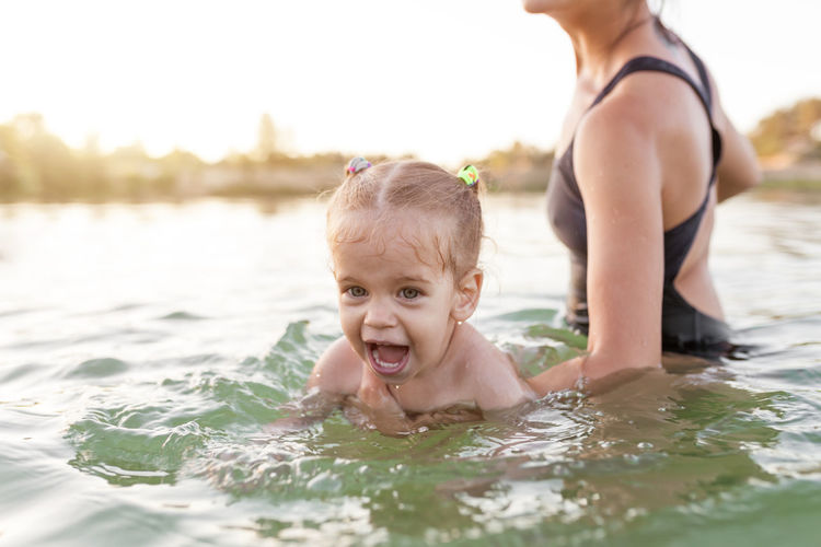 Cute girl with mother swimming in lake