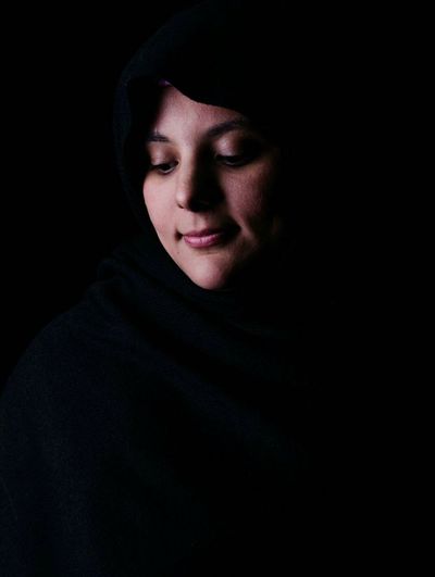 Woman looking away against black background