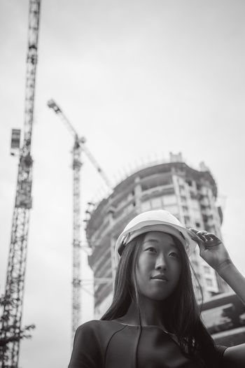 Low angle view of young woman standing in city against clear sky