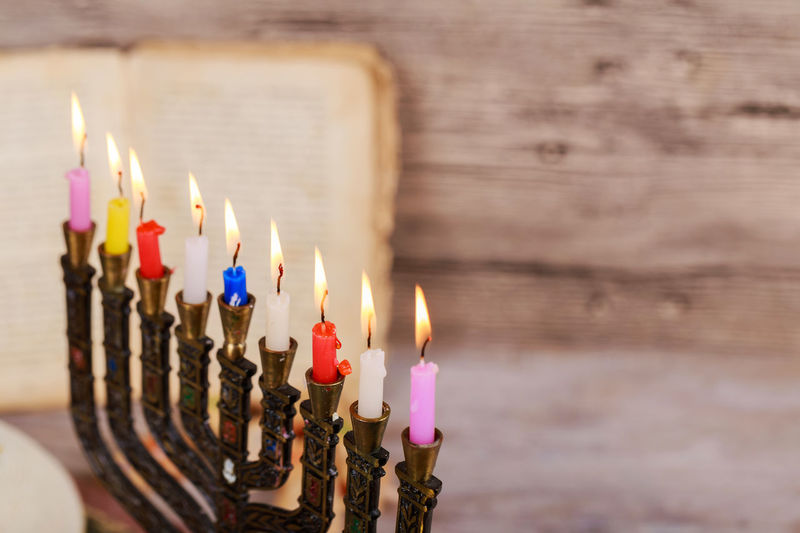 High angle close-up of lit colorful candles on wooden table