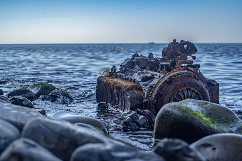 Old rusty engine lying among stones in the water