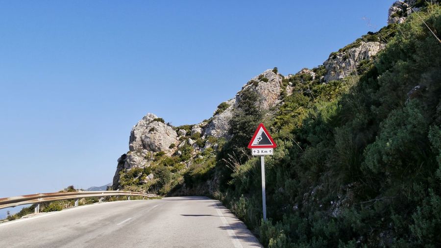 Road sign by tramuntana mountain road against sky