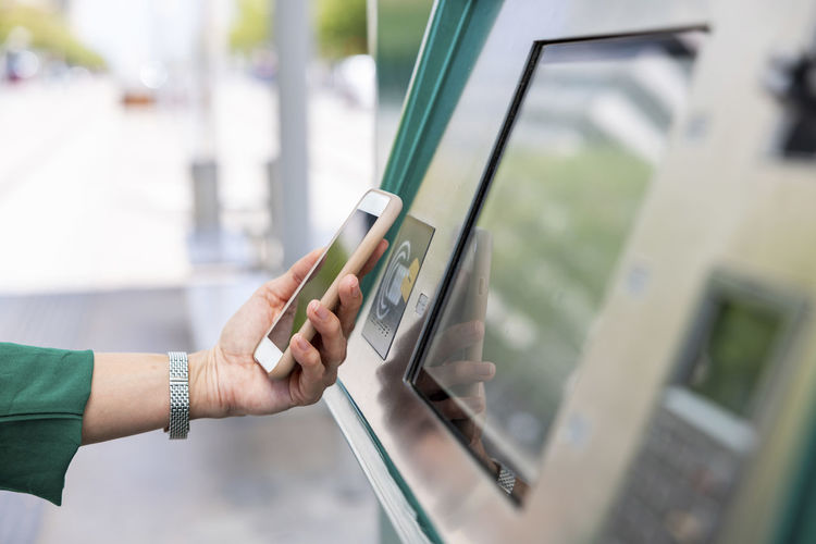 Hand of woman scanning on ticket machine with smart phone