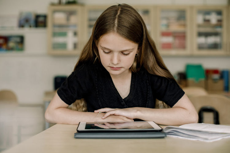 Female student looking at digital tablet while sitting in classroom