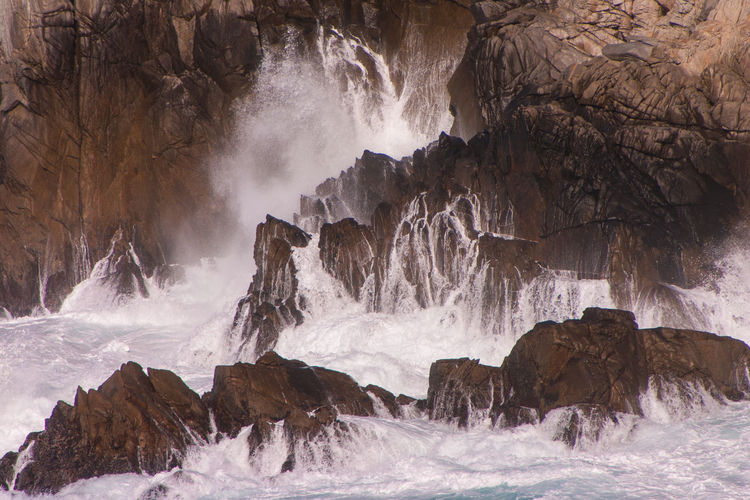 Panoramic view of crashing ocean waves against cliffside rocks