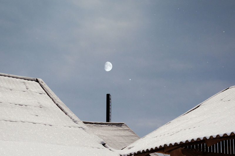 Low angle view of snow covered roof against sky