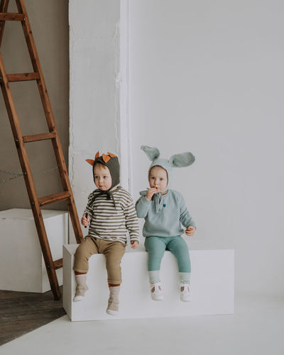 Toddler twins in funny hats with ears sitting and smiling