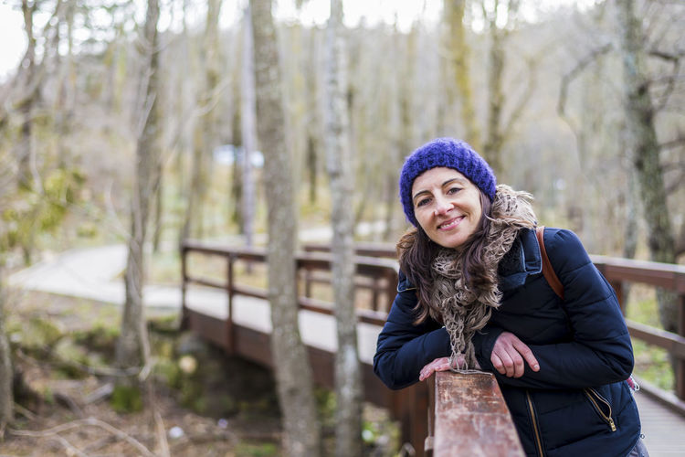 Portrait of woman leaning on footbridge during winter