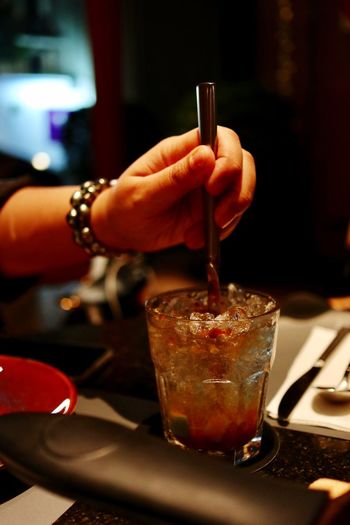 Cropped hand of woman mixing drink on table in restaurant