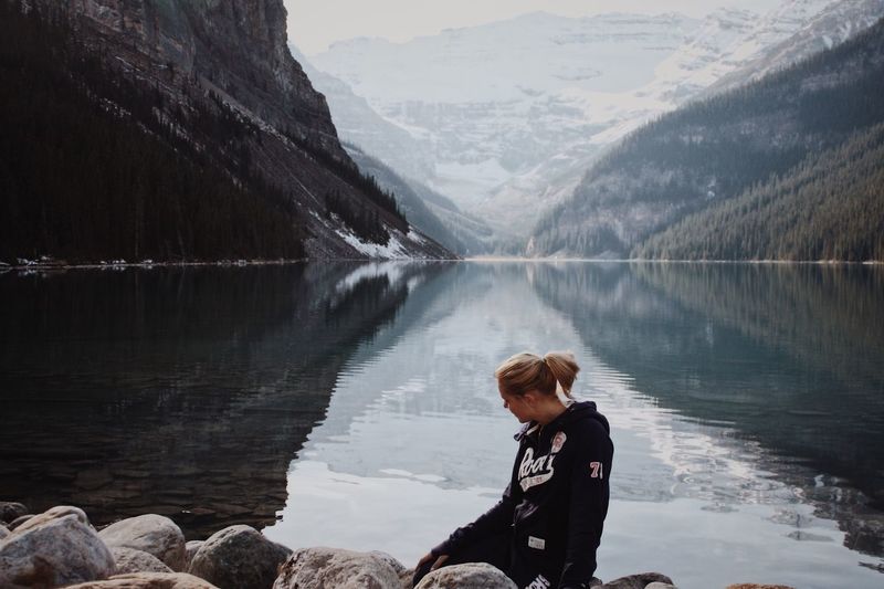Woman sitting on rock against lake