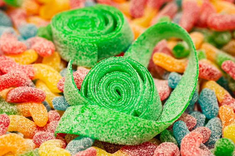 Close-up, background with green rolled gummies coated with sugar.