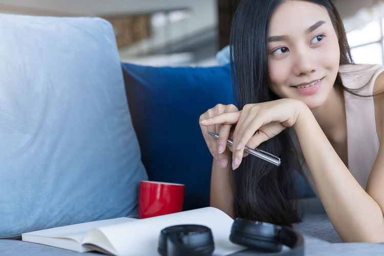 Portrait of young woman holding smart phone while sitting on table