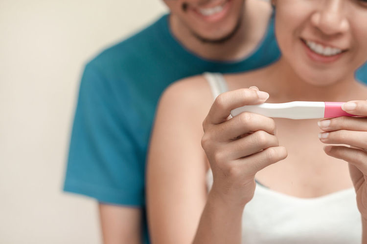 Midsection of happy couple looking at pregnancy test