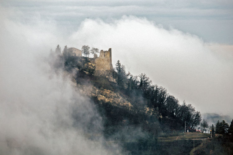 Unique view of medieval canossa castle in the fog during a cold winter day, emilia romagna, italy