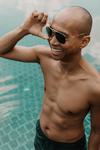 Shirtless man wearing sunglasses in swimming pool