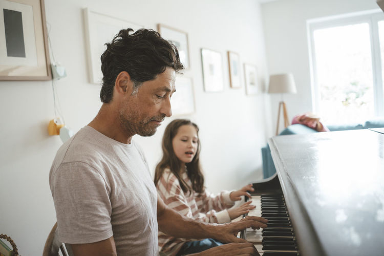 Father and daughter playing piano together at home