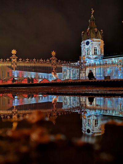 Reflection of illuminated building in puddle at night