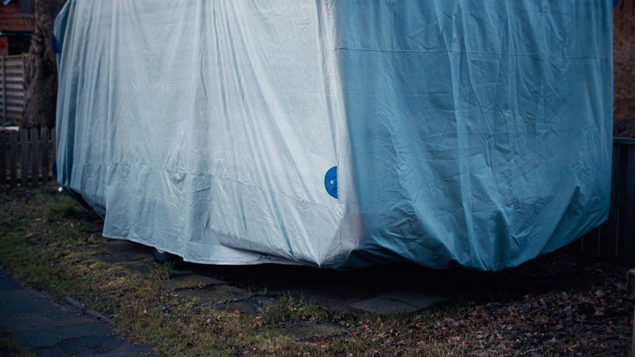 Close-up of cover over camper trailer on land in backyard