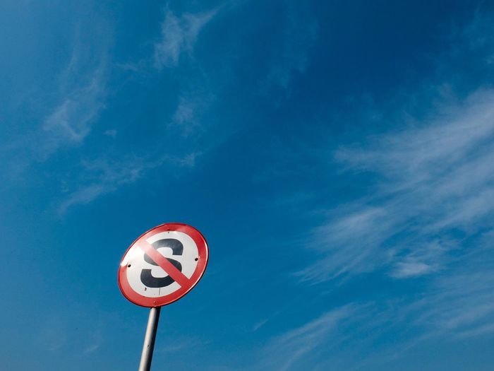 Close-up of road sign against sky