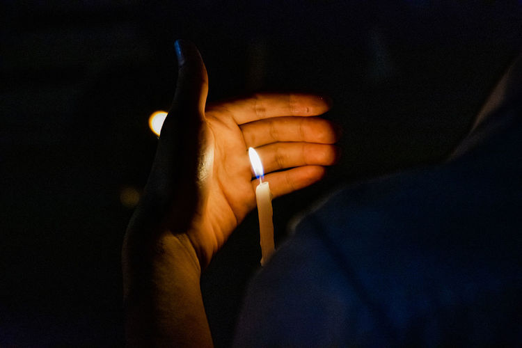 Close-up of person holding candle in darkroom