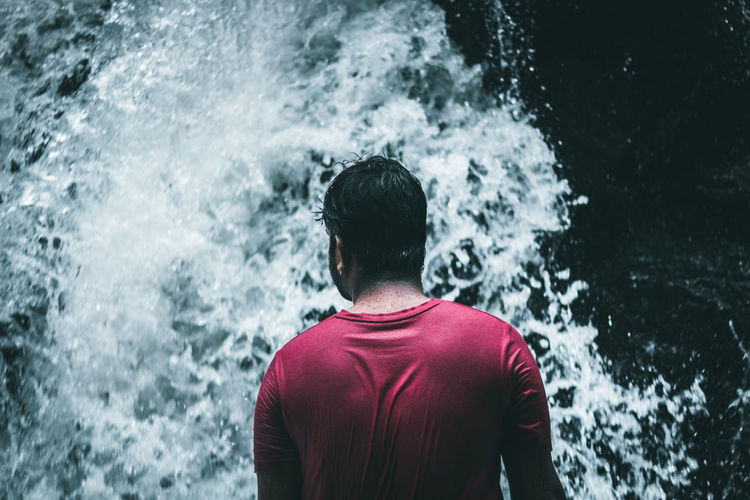 Rear view of man standing by waterfall