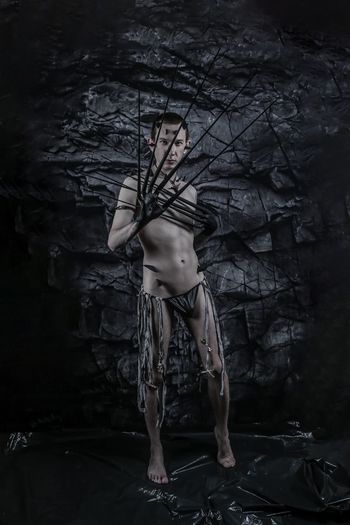 Rear view of a shirtless man standing in a cave