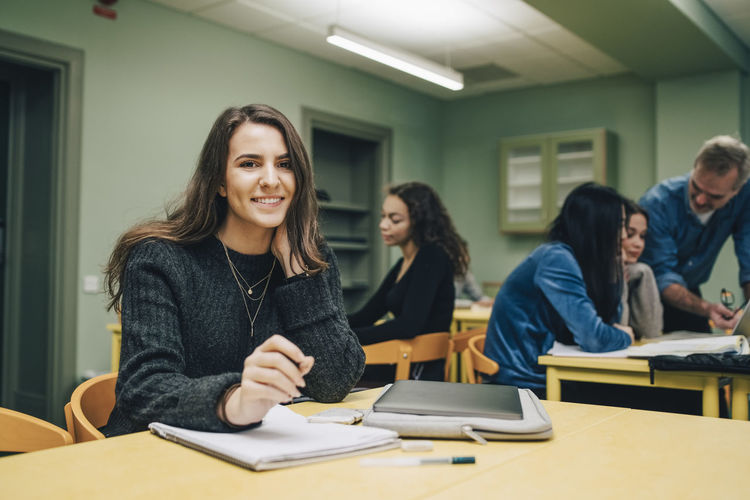 Portrait of smiling female student at desk in classroom