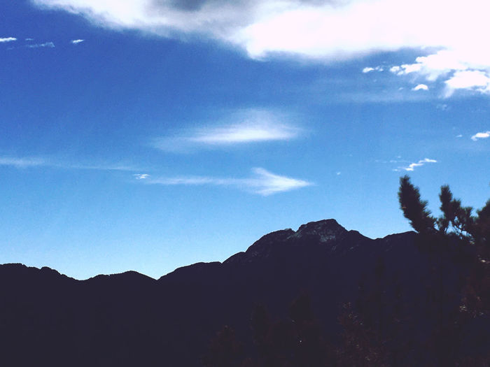 Low angle view of silhouette mountain against blue sky