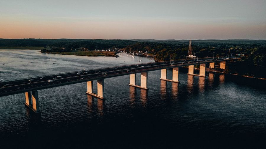 Pier over river against sky during sunset