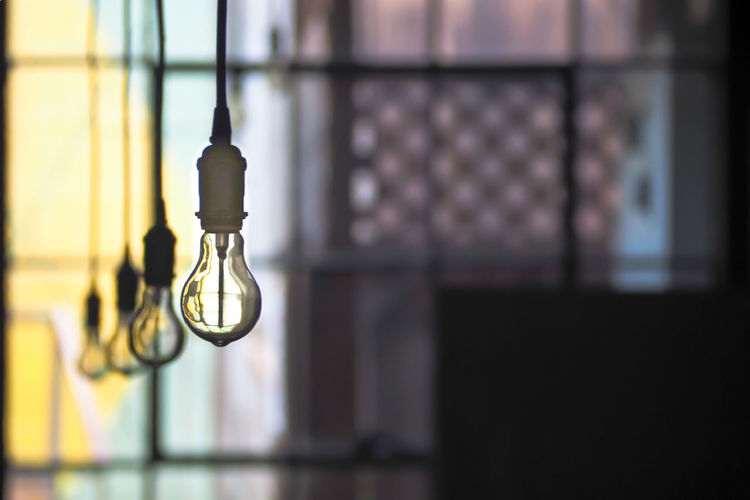 Close-up of light bulb hanging against wall