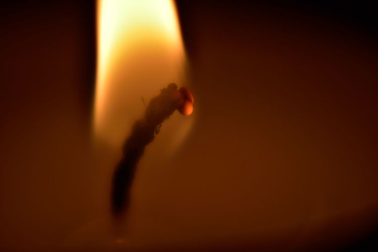 Close-up of lit tea light candle in dark room
