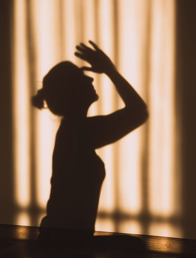 Silhouette woman sitting on hardwood floor