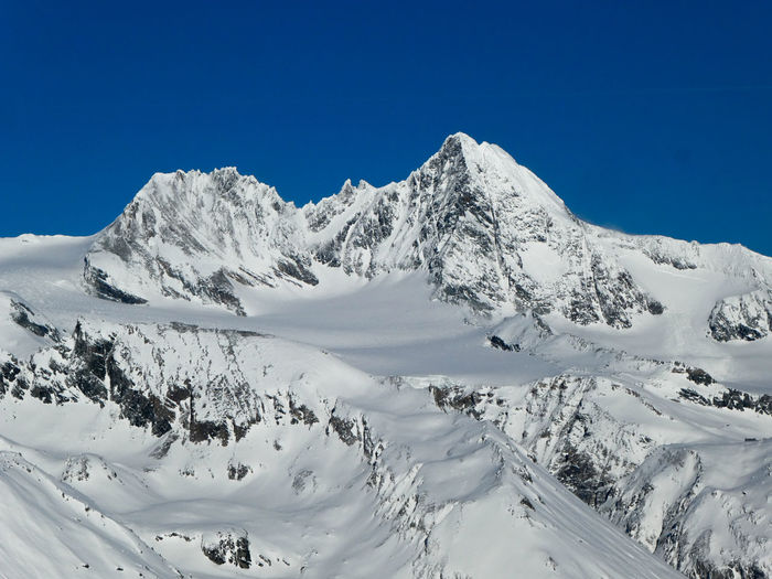 Scenic view of snowcapped mountains against clear blue sky