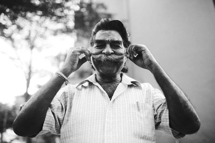 Portrait of man holding mustache