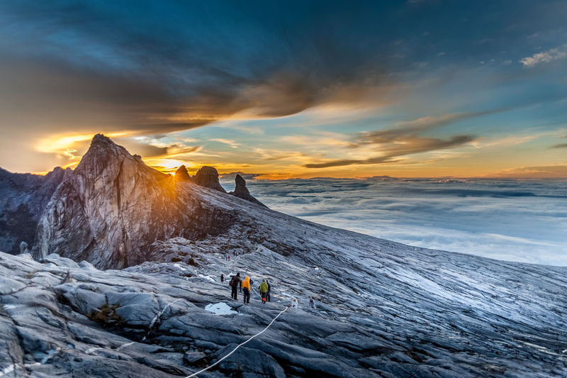 People on snowcapped mountain against sky during sunset
