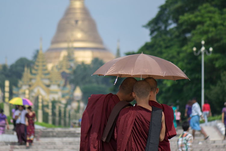 Rear view of monks under umbrella standing at shwedagon pagoda