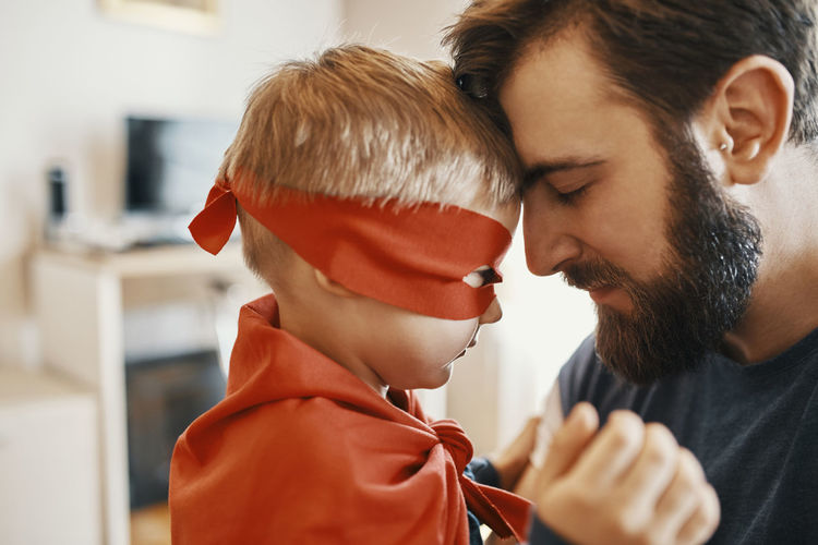 Little boy dressed up as a superhero head to head with his father