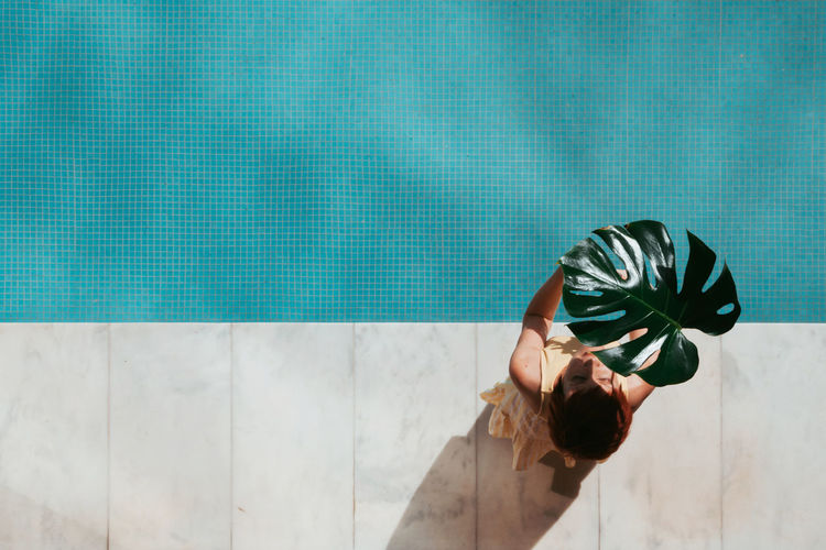 YOUNG WOMAN IN SWIMMING POOL AGAINST WALL