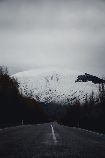 Road by snowcapped mountain against sky