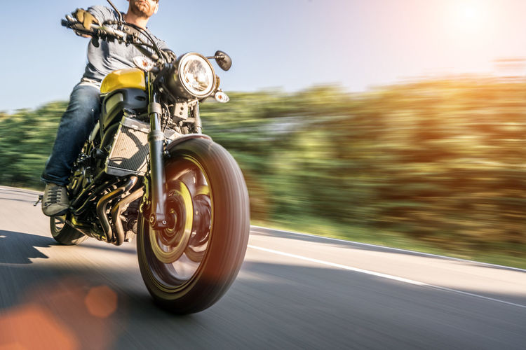 Low section of man riding motorcycle on road